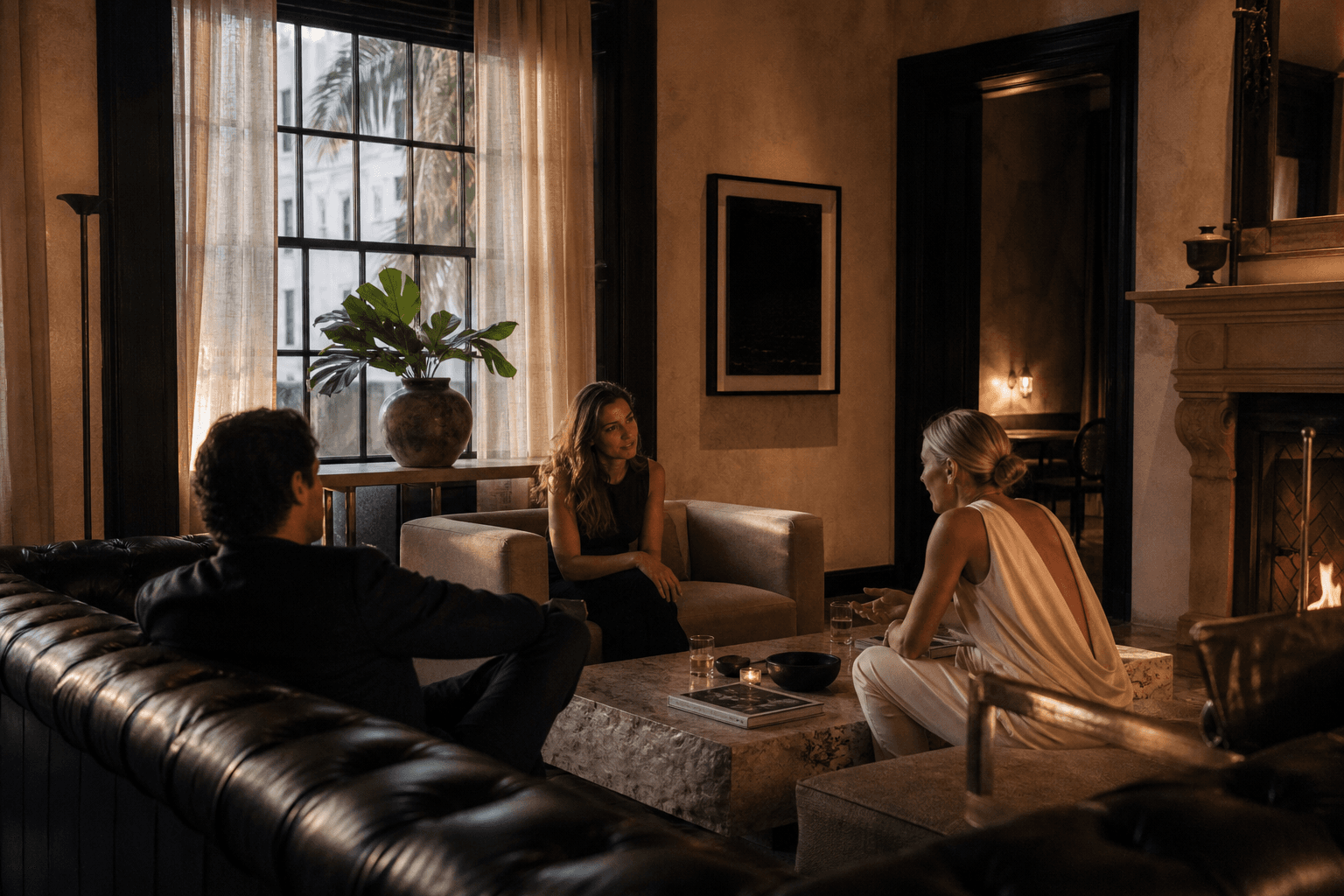 Members in conversation in a quiet sitting room with leather, stone, and late light.