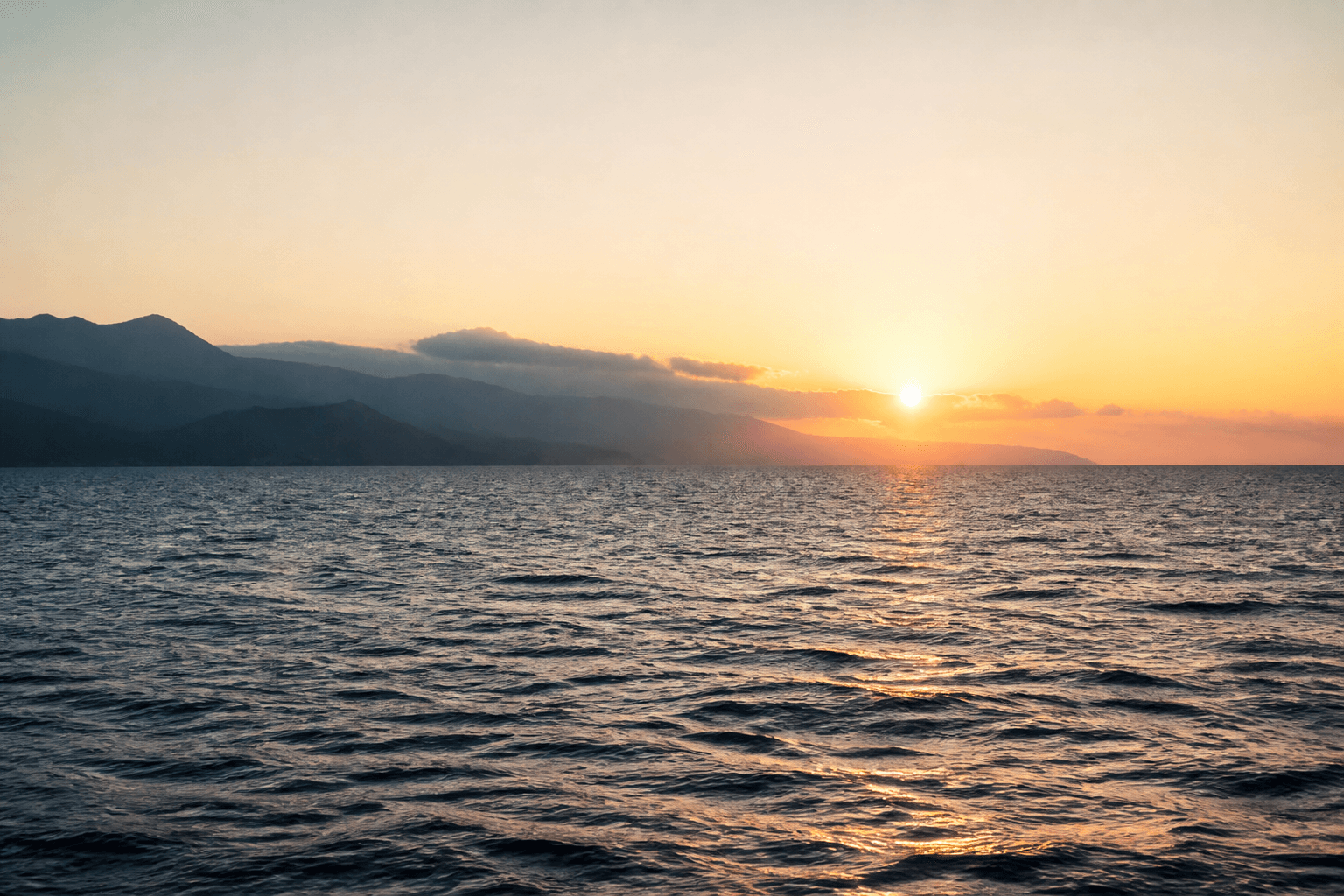 Open water and distant coastline at sunrise.